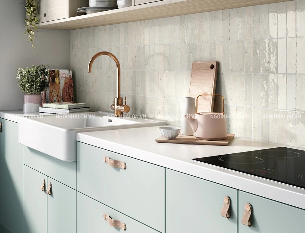 Phòng bếp phối gạch ốp tường màu trắng sữa cùng tone pastel với tủ bếp.